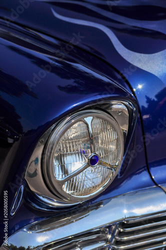 Blue Vintage Car Headlight Detail - Close-up detail of a headlight and bodywork on a blue vintage automobile.

