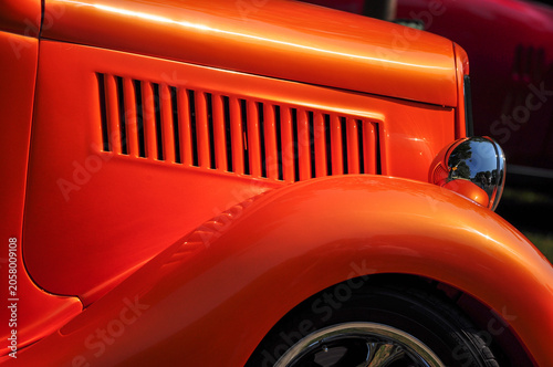 Orange Classic Automobile Side Detail - Close-up view of the side bodywork and ventilation slots of an orange classic automobile.