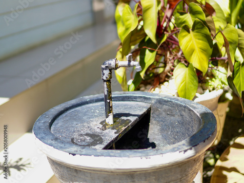 A rustic outdoor hand washing station featuring a metal water spigot installed over a round concrete basin