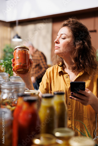 Foto Healthy living woman in zero waste store using smartphone notes app to check shopping list while meticulous customer looking to replenish pantry at home with natural pesticides free food essentials