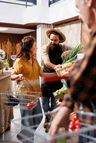 Photos Newly opened zero waste shop owner showing clients freshly received batch of organic food while entrepreneur inviting customers in local neighborhood store after grand opening