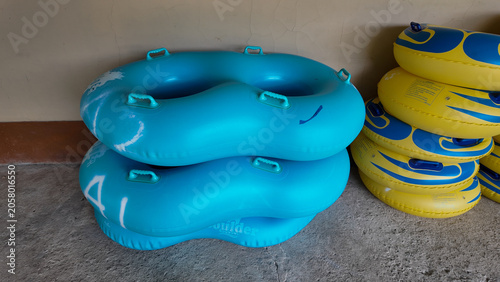 Photos Stack of colorful inflatable inner tubes in blue and yellow resting against a wa
