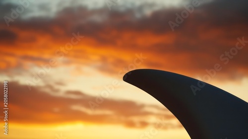Close-up of a surfboard fin against a sunset sky.