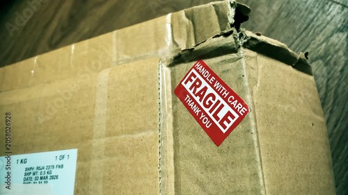 Close-up of damaged cardboard parcel with red fragile handle with care sticker