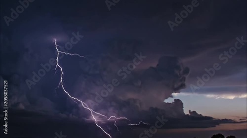 Dramatic lightning strike illuminating dark stormy night sky over horizon
