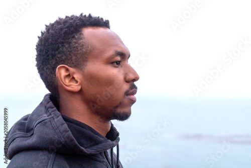 Fotografie Man in a hoodie gazing at the ocean, profile view.