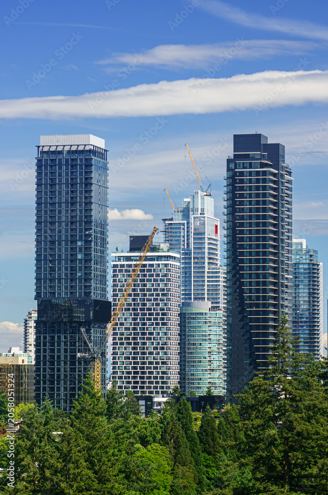 Fototapeta premium Vibrant skyline of Burnaby showcases modern high-rises against a brilliant blue sky in summer