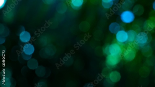 Abstract blurry bokeh lights in dark green and blue hues creating a dreamy background suitable for