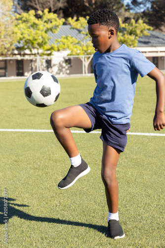 Obraz na plátně African American male child juggling soccer ball while wearing blue tshirt navy