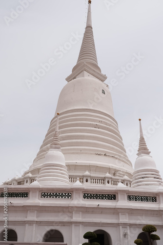 Grand traditional Buddhist stupa with smaller twin chedis under a cloudy sky.