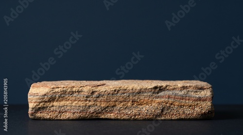 Eye-level macro view of a stratified sedimentary sand block podium