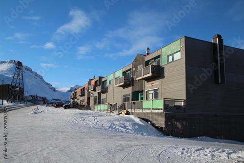 Longyearbyen town panorama in Svalbard, Norway. Remote arctic settlement with colorful houses, traditional wooden architecture, industrial heritage under winter snow and majestic polar mountains.