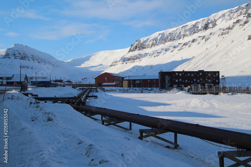 Longyearbyen town panorama in Svalbard, Norway. Remote arctic settlement with colorful houses, traditional wooden architecture, industrial heritage under winter snow and majestic polar mountains.