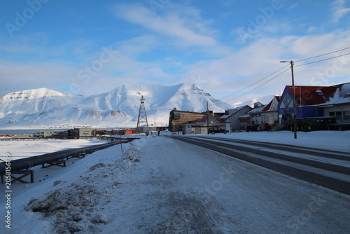 Longyearbyen town panorama in Svalbard, Norway. Remote arctic settlement with colorful houses, traditional wooden architecture, industrial heritage under winter snow and majestic polar mountains.