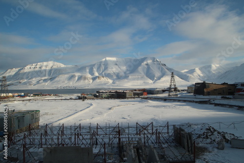 Longyearbyen town panorama in Svalbard, Norway. Remote arctic settlement with colorful houses, traditional wooden architecture, industrial heritage under winter snow and majestic polar mountains.
