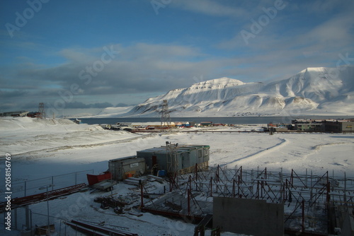 Longyearbyen town panorama in Svalbard, Norway. Remote arctic settlement with colorful houses, traditional wooden architecture, industrial heritage under winter snow and majestic polar mountains.
