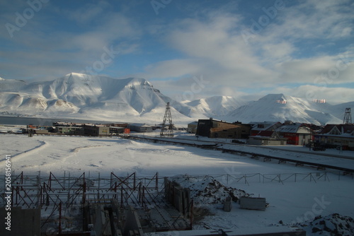 Longyearbyen town panorama in Svalbard, Norway. Remote arctic settlement with colorful houses, traditional wooden architecture, industrial heritage under winter snow and majestic polar mountains.