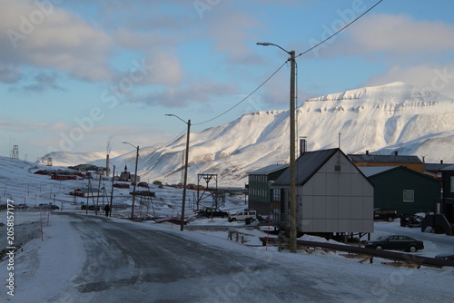 Longyearbyen town panorama in Svalbard, Norway. Remote arctic settlement with colorful houses, traditional wooden architecture, industrial heritage under winter snow and majestic polar mountains.
