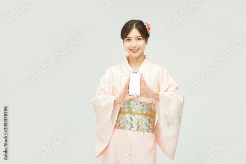 Photography Smiling young woman in pink kimono holding smartphone