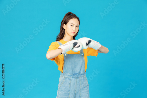 Принти на полотні Young woman in boxing gloves posing confidently on blue background