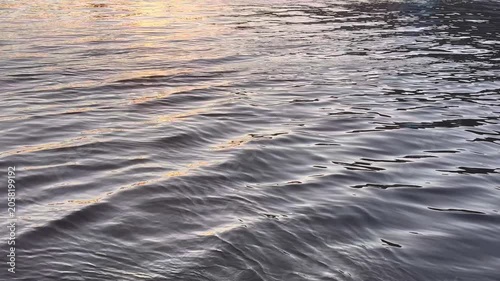 Water flowing gently from the lakeside creating tiny wavelets at sunset