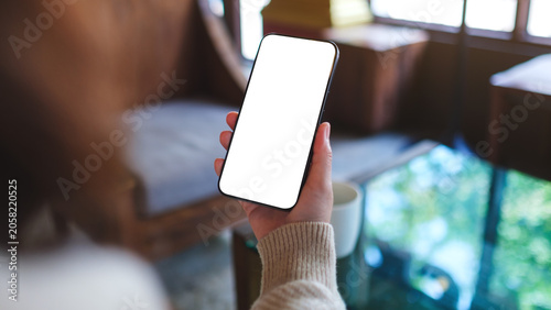 Fotografi Mockup image of a woman holding and using mobile phone with blank desktop screen