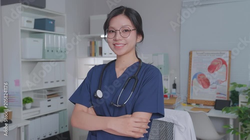 young asian female doctor wearing lab coat and stethoscope smiles with crossed arms, woman exuding confidence and professionalism.