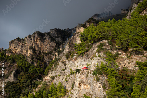 Photos POSITANO, ITALY - OCTOBER 01, 2018: A red firefighter truck drives along a narrow, winding cliffside road to reach a forest fire area