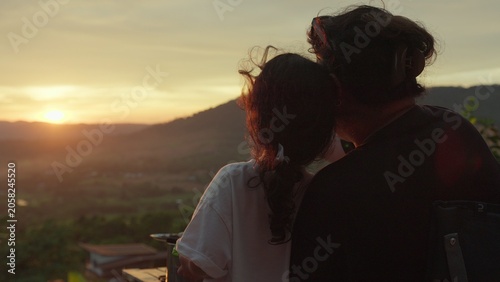Quadro su tela A mother and daughter watch the sunset over mountains from a viewpoint, sharing a quiet moment of family bonding and appreciating the tranquil scenic view