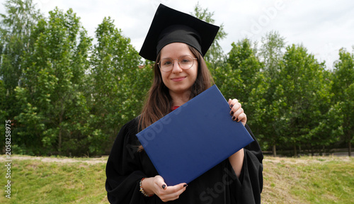 young smiling female graduate with diploma, master of arts, bachelor, graduation ceremony, robe