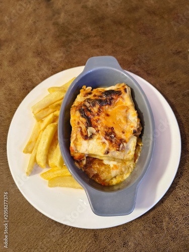 Top view of a savory baked lasagna served with french fries on a white plate