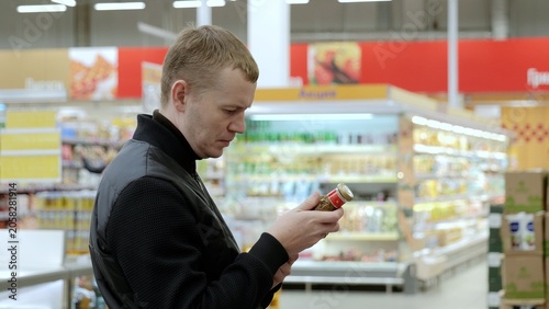 Φωτογραφία Careful customer reads product label in brightly lit supermarket aisle, making thoughtful healthy choice