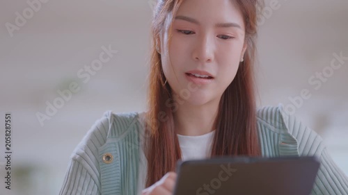 Smiling asian business woman using tablet laptop with equipment placed for doing finance on an home office desk, tax, report, accounting, statistics, and analytical research concept.
