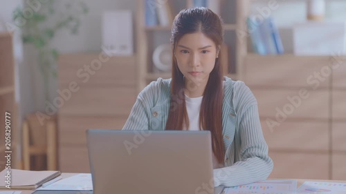 Young asian professional woman working on her laptop in a modern home office, focused on tasks and demonstrating productivity in a corporate environment. Smart freelancer working.