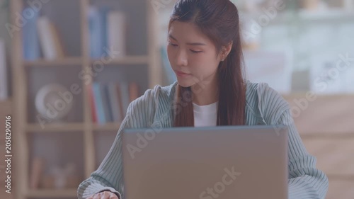 Smiling asian business woman using tablet laptop with equipment placed for doing finance on an home office desk, tax, report, accounting, statistics, and analytical research concept.
