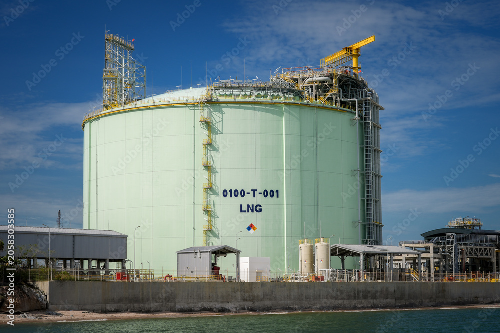 Obraz premium Liquefied natural gas storage tank energy industry terminal refinery gas fuel, large cryogenic vessel at coastal port facility with ladder and crane under blue sky, industrial safety mood