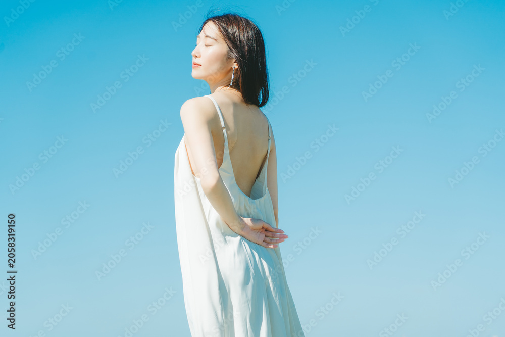 Obraz premium 青空背景の夏服の若いアジア人女性