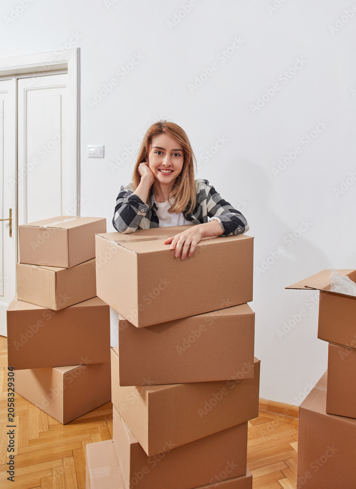 Fototapeta premium Happy woman leaning on stacked moving boxes