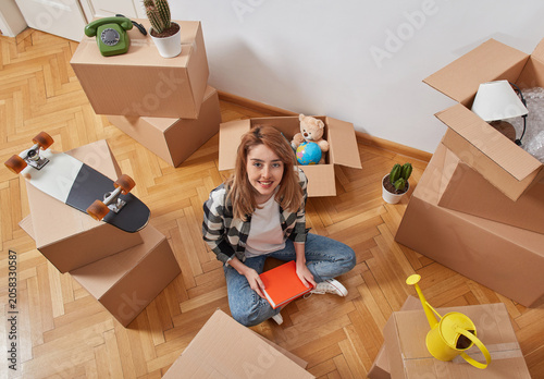 Woman unpacking books surrounded by moving boxes