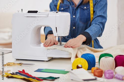 Fashion designer operating sewing machine in tailoring studio