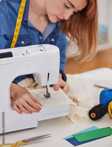 Seamstress sewing fabric on modern sewing machine