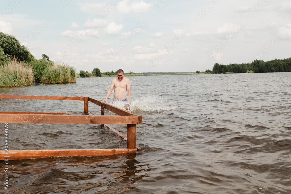 Fototapeta premium dynamic, relaxed shot boy jumping into natural lake. child is captured mid flight, creating sense excitement. image perfect family vacations, water safety, promoting active lifestyle among children