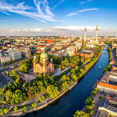 Aerial view of a European city's historic center with a river, featuring a large church with a green dome and a tall tower