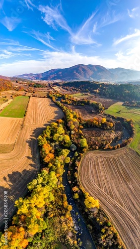 Aerial view of a serene landscape with fields, trees, and mountains