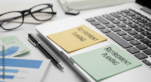 Close-up of retirement planning documents and office supplies on a laptop