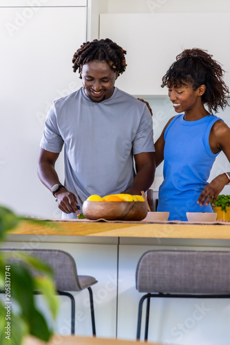 African American couple preparing food at wooden island, using cutting board with lemons