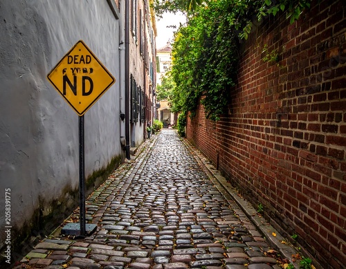 Weathered Dead End Street Sign Standing in Narrow Cobblestone Alleyway