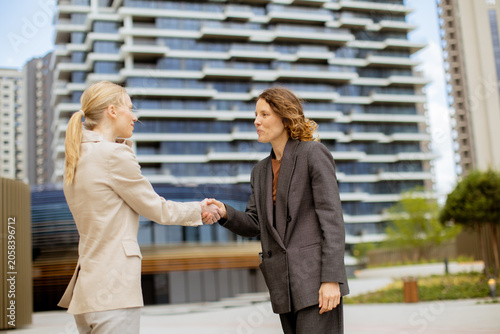 Women shake hands in front ...