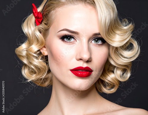 Glamorous Blonde Woman with Curly Hair and Red Lipstick Posing Against Dark Studio Background