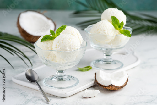 Coconut ice cream in glass bowls on the table. A refreshing tropical summer dessert. Selective focus.